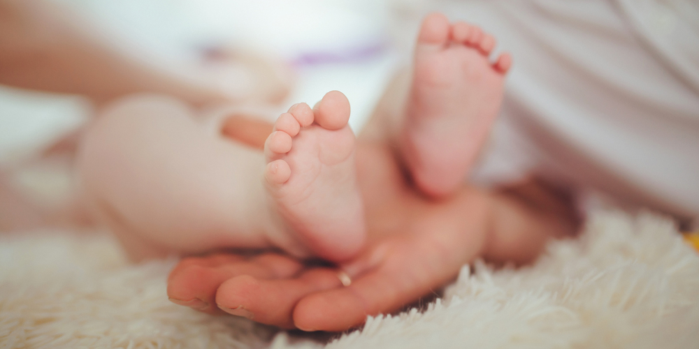 Kinderwunsch – kleine Babyfüsse in großen Händen